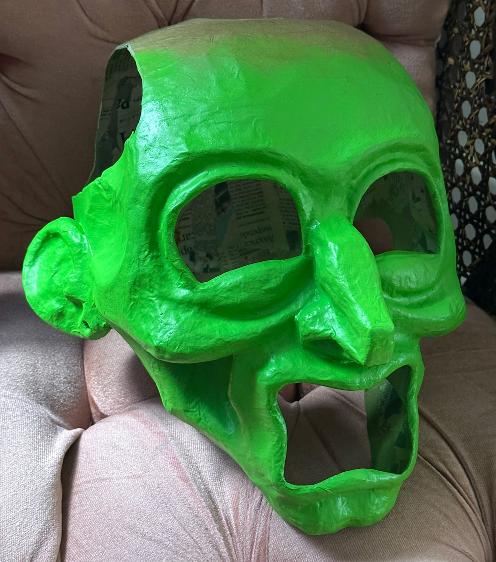 Paper mache male human head mask, spray painted a solid bright green color.