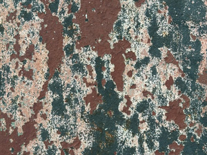 Mottled dark green, dark brown, and light brown surface of corroded old metal with paint peeling
