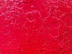 Shiny red paint on a pitted metal surface