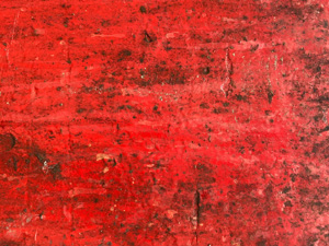 Weathered red paint on corroded metal