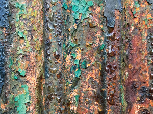 Morning dew on peeling green paint on rusted metal