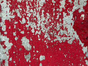 Scraped red paint revealing light gray concrete surface