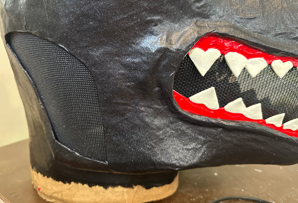 side view of the mask, showing the thick screen at the sides of the head, and the more transparent screen in the mouth