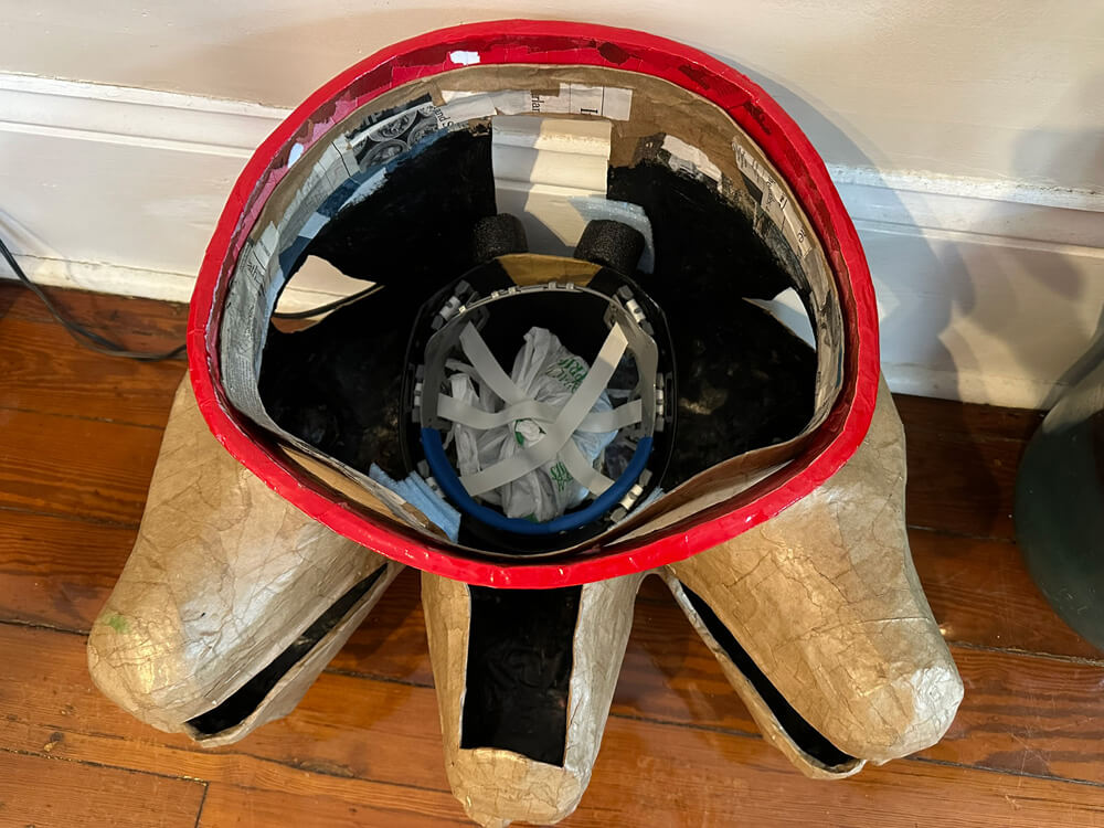 Wider view of the upside down mask with the hard hat sitting in it