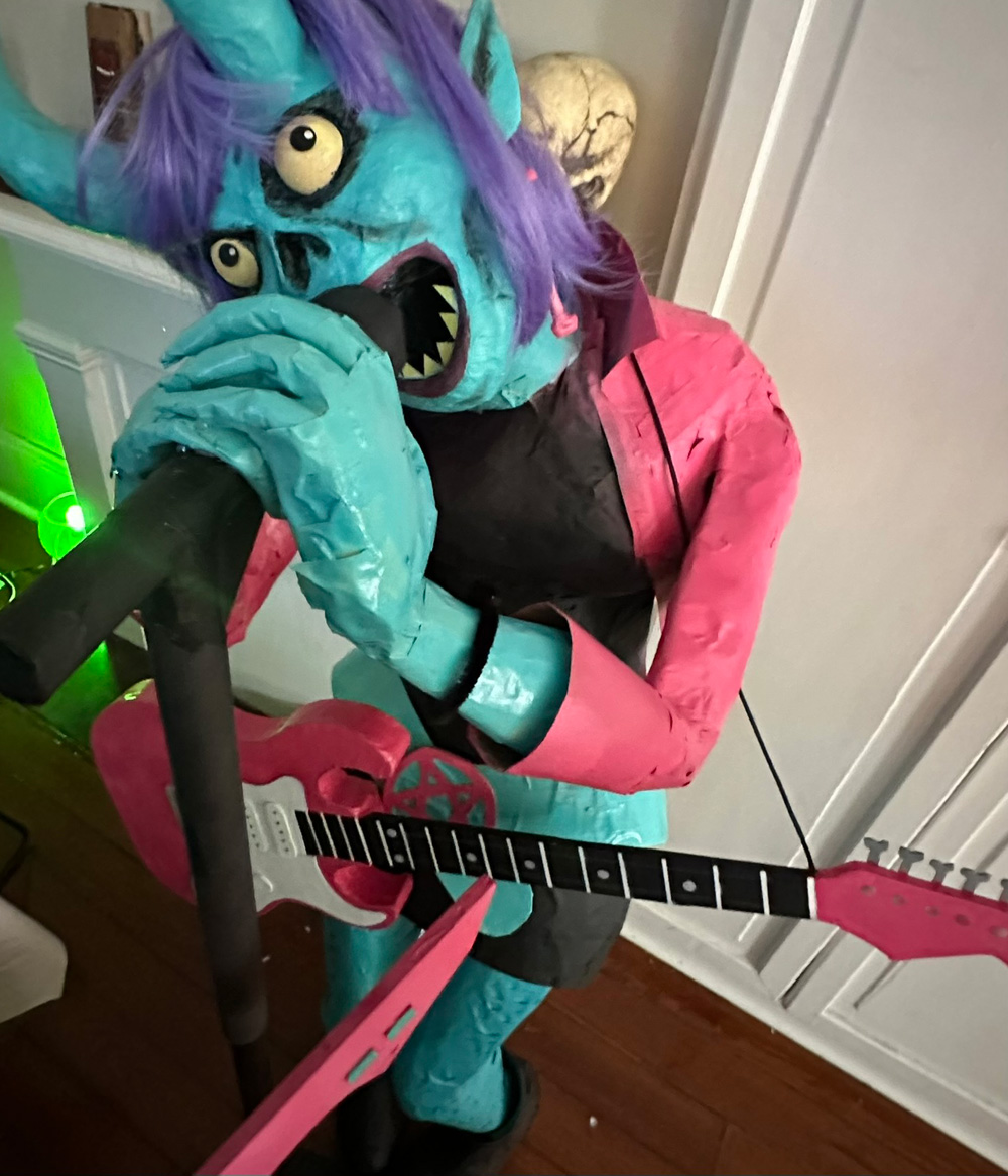 My demonic singer prop with the guitar prop hanging around her shoulders as she puts both hands on the microphone