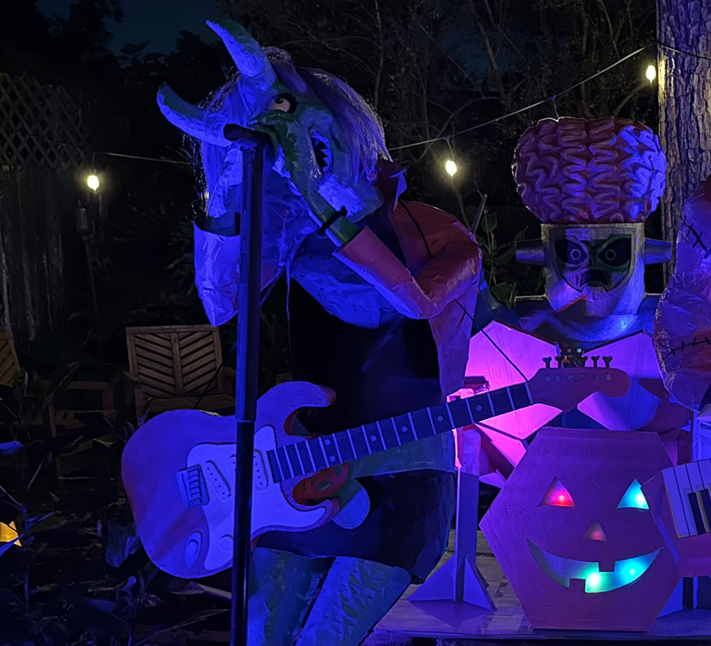 The demonic singer prop outside at night with the guitar prop hanging around her shoulders