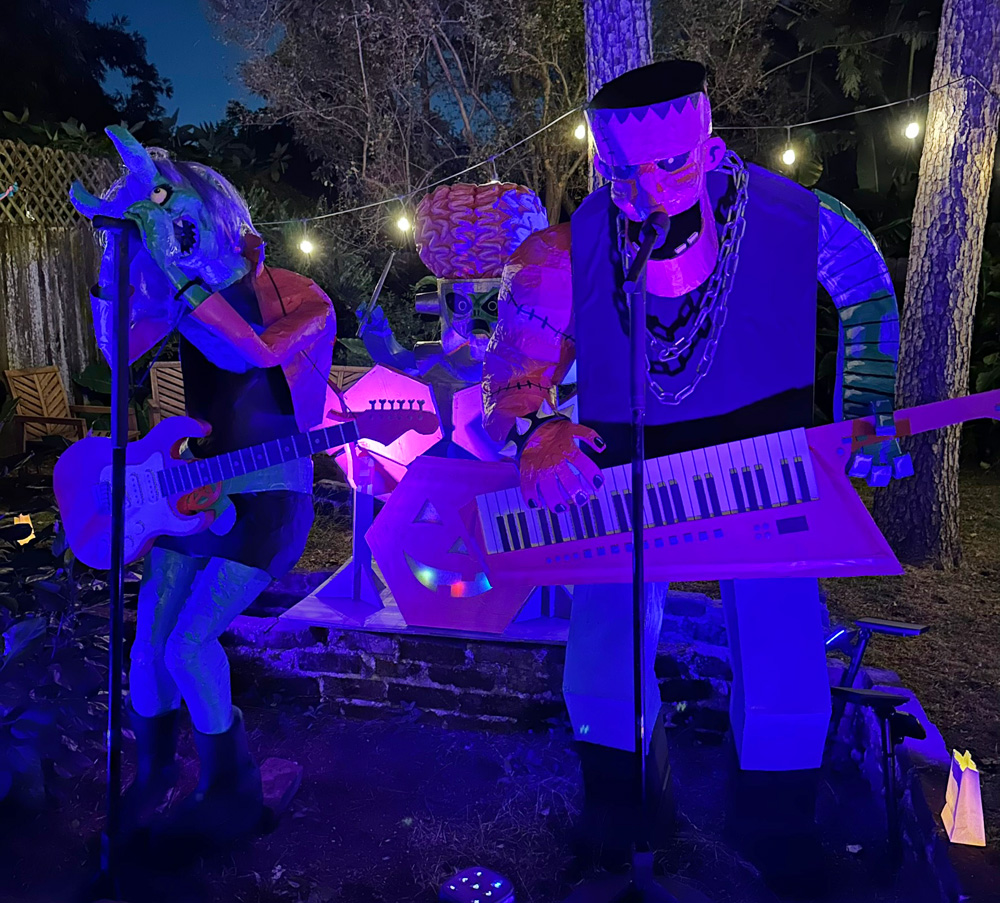 The whole band set up together at night; demonic singer/guitarist lady, Frankenstein keytar player, and alien drummer.