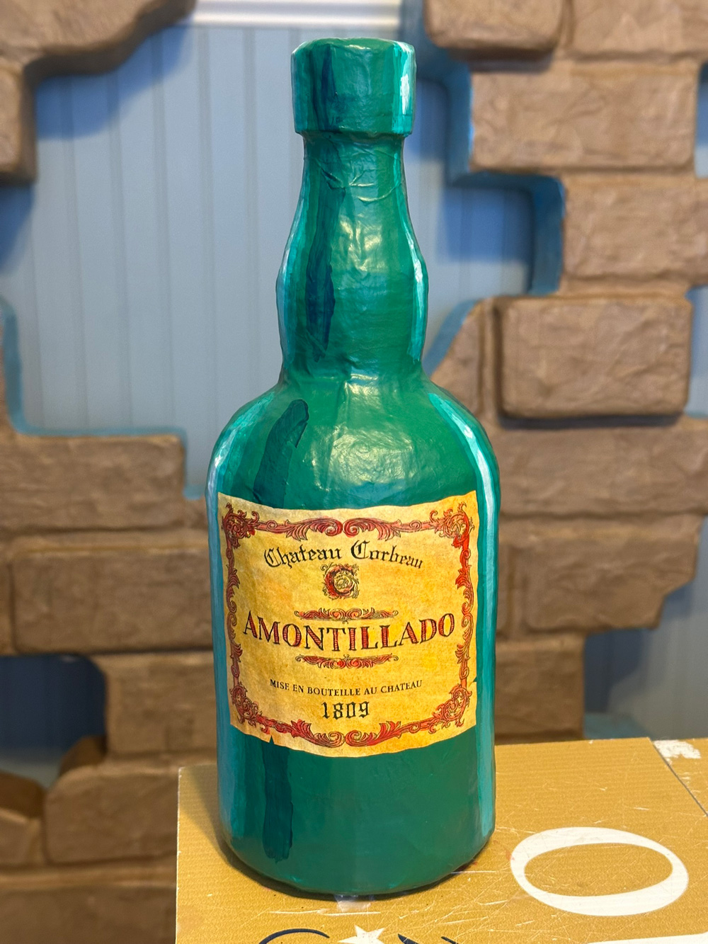 Green paper mache liquor bottle with yellow label.