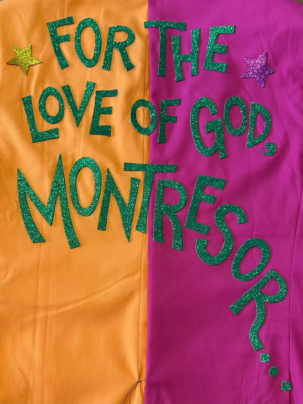 The back of my suit, orange on the left, magenta on the right, with green letters that spell out For the love of god, Montresor!