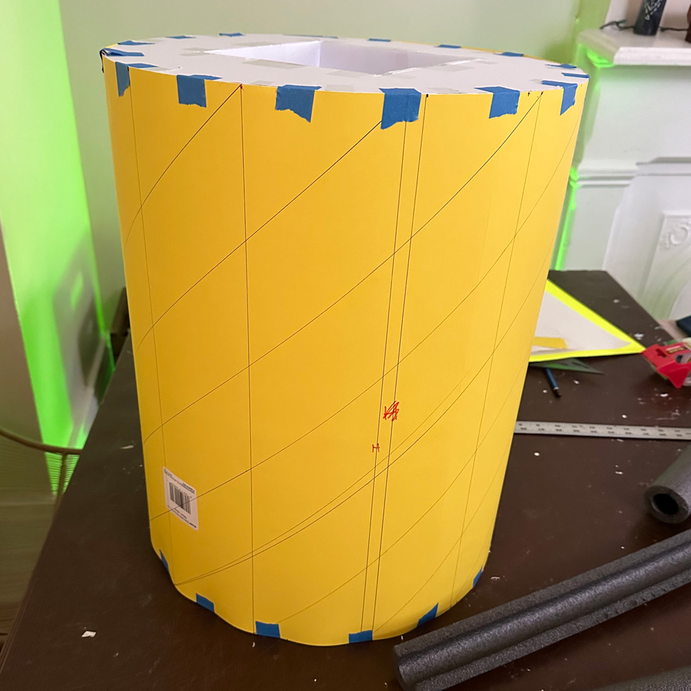 A big cylinder of yellow poster board, covering the foam board shapes.