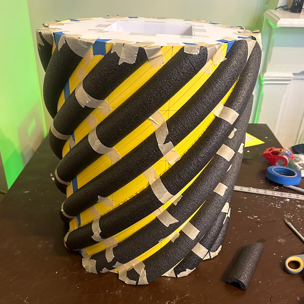 Black foam tubes arranged in a spiral shape around the poster board cylinder.