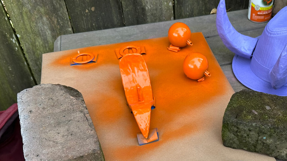 The tongue and nose ring and eyes, laid out on a piece of paper and spray painted orange