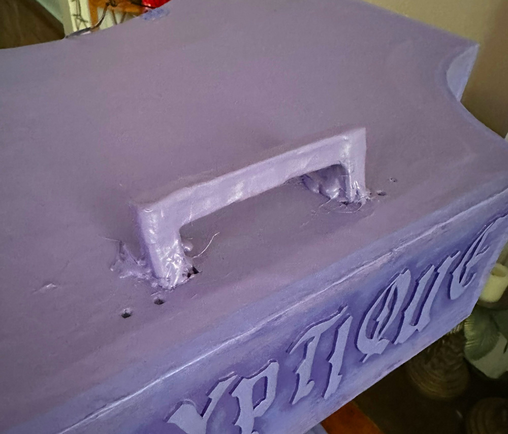 A purple wooden handle on the top purple surface of the paper mache column