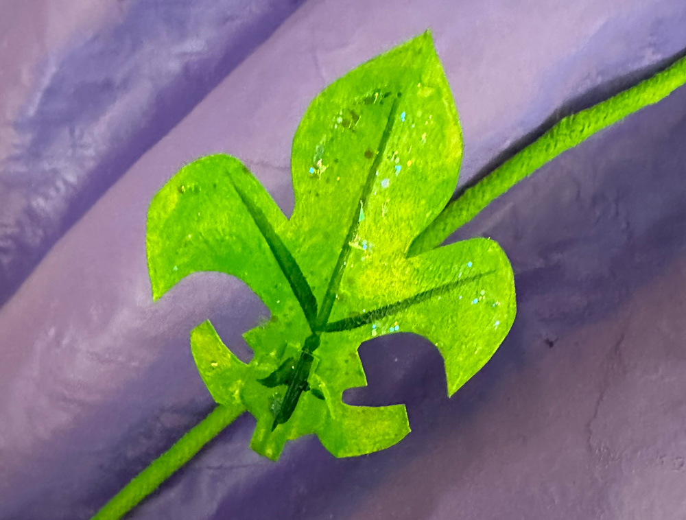 Close up of a green glittery leaf shaped like a fleur-de-lis.