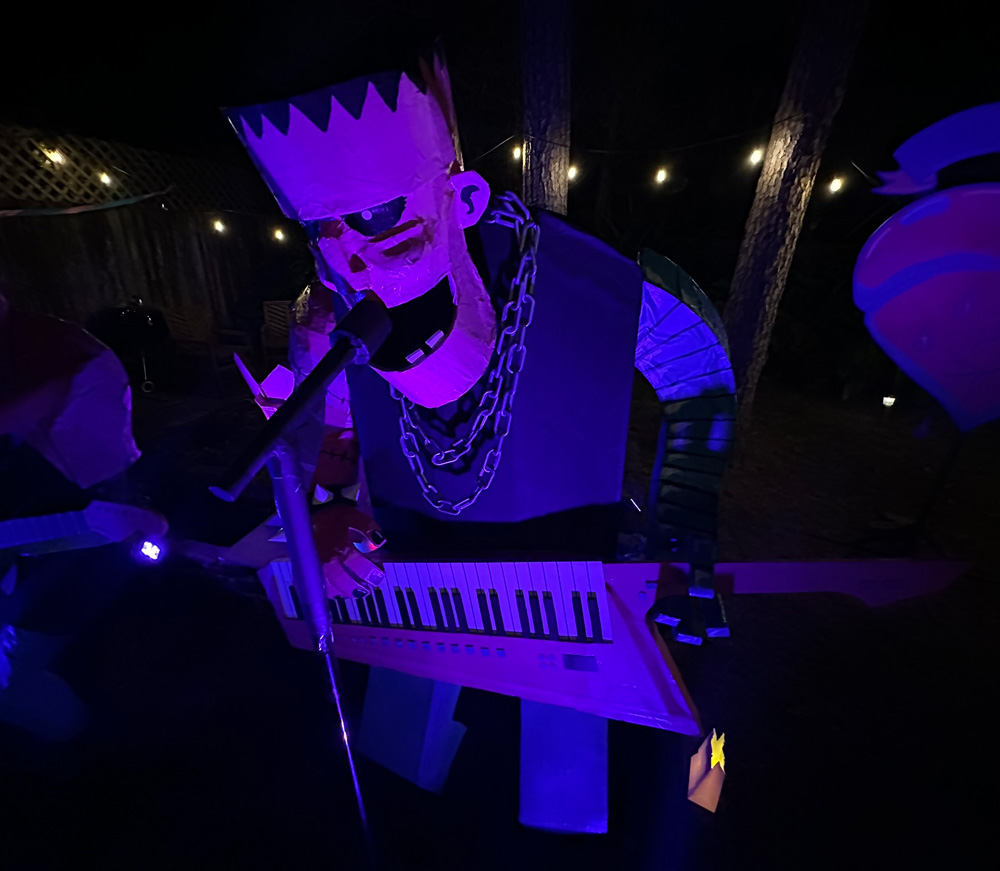 The Frankenstein statue set up in our yard at night with spooky blue purple lighting.