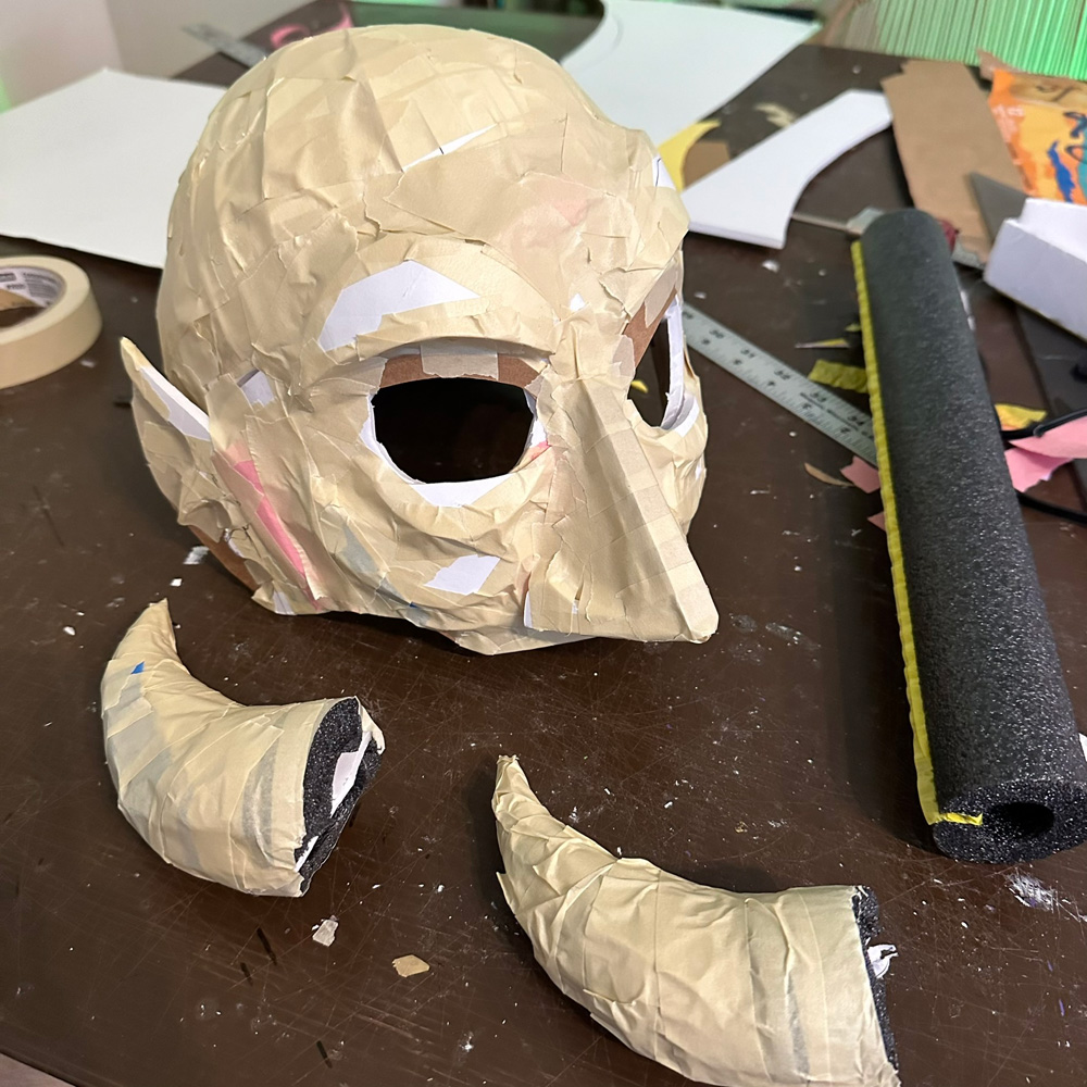 Ears added, horns are lying on the table in front of the mask.