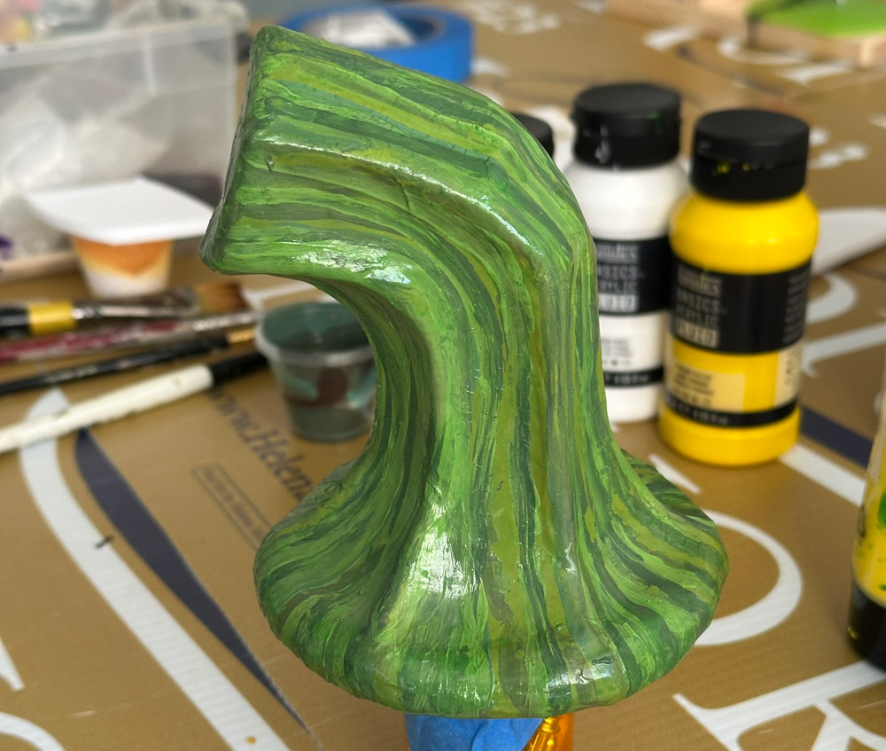 The stem is now painted with striated lines of different shades of green.