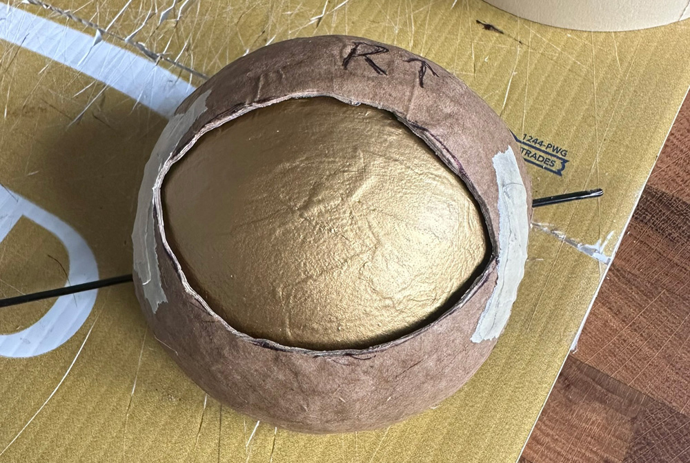 One of the gold eyeballs sitting behind its paper mache eyelid.