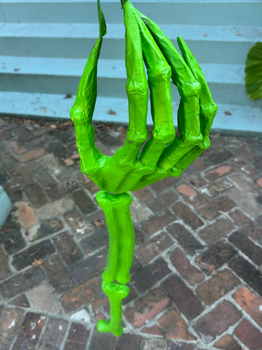The arm hanging vertically after it's been spray painted bright green.