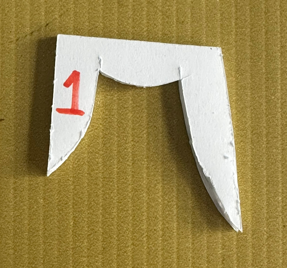 A cut out foam board shape representing a bent finger as seen from the side.
