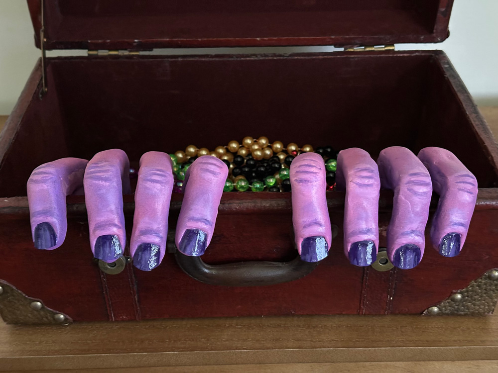 The completed monster hands poking out from inside of an old suitcase.
