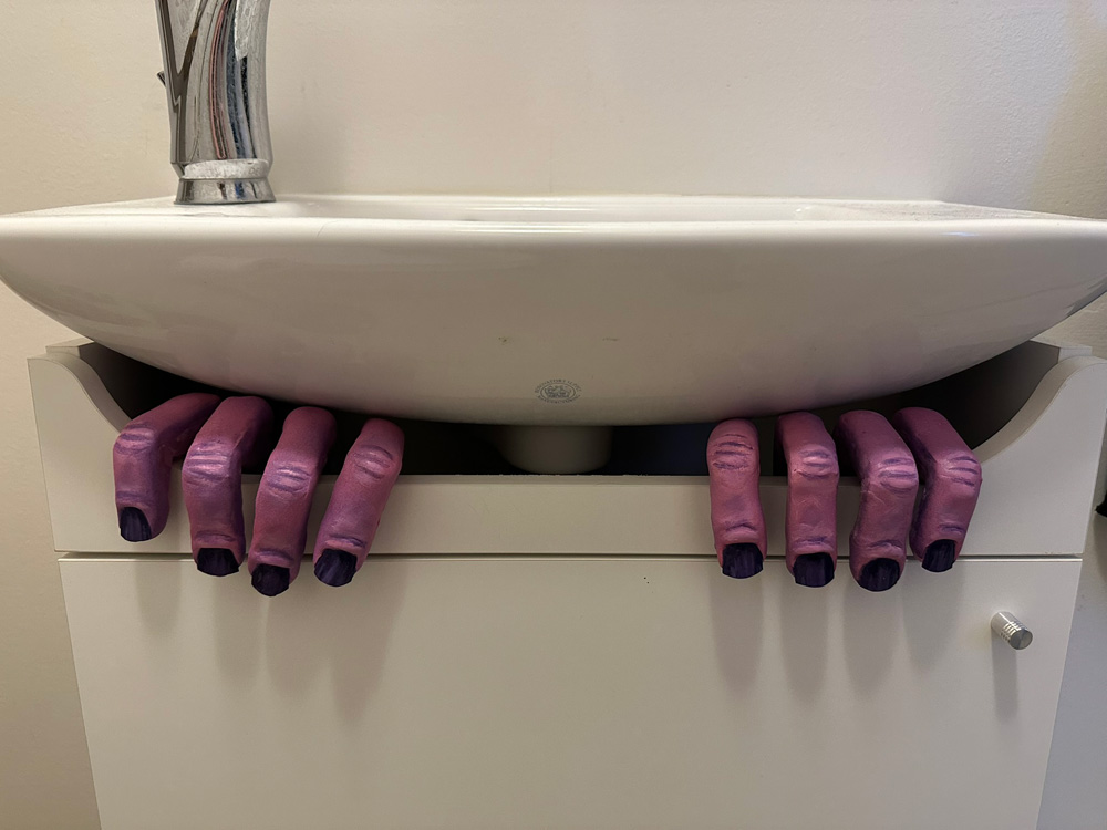 The monster hands, set into the open space on top of a small white cabinet under a sink.