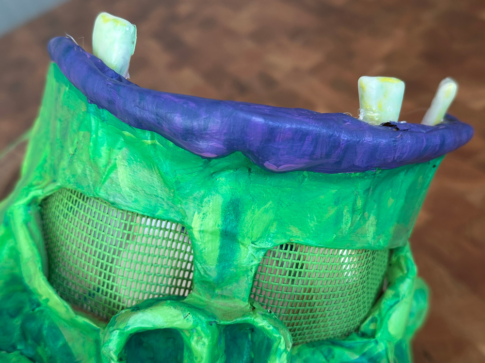 Close up of the front of the mask showing the painted screen material in the eye holes and the thermoplastic teeth.