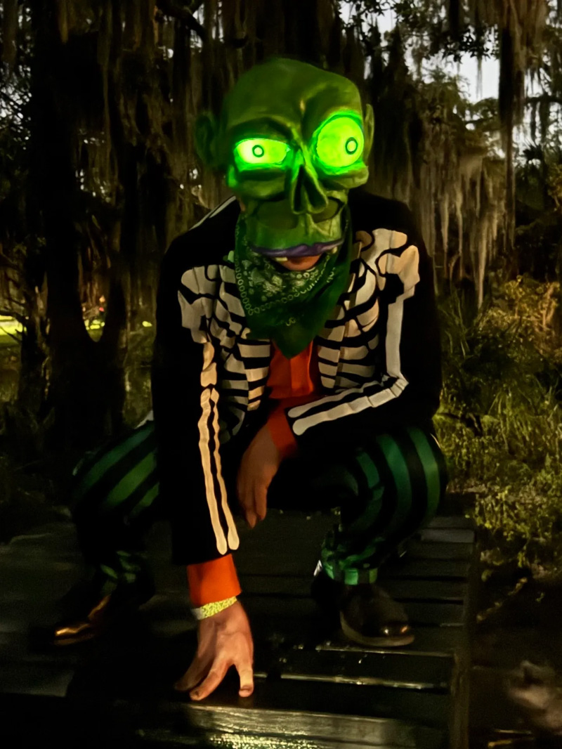 Me wearing the zombie mask and crouching spookily on a wooden table in the park.