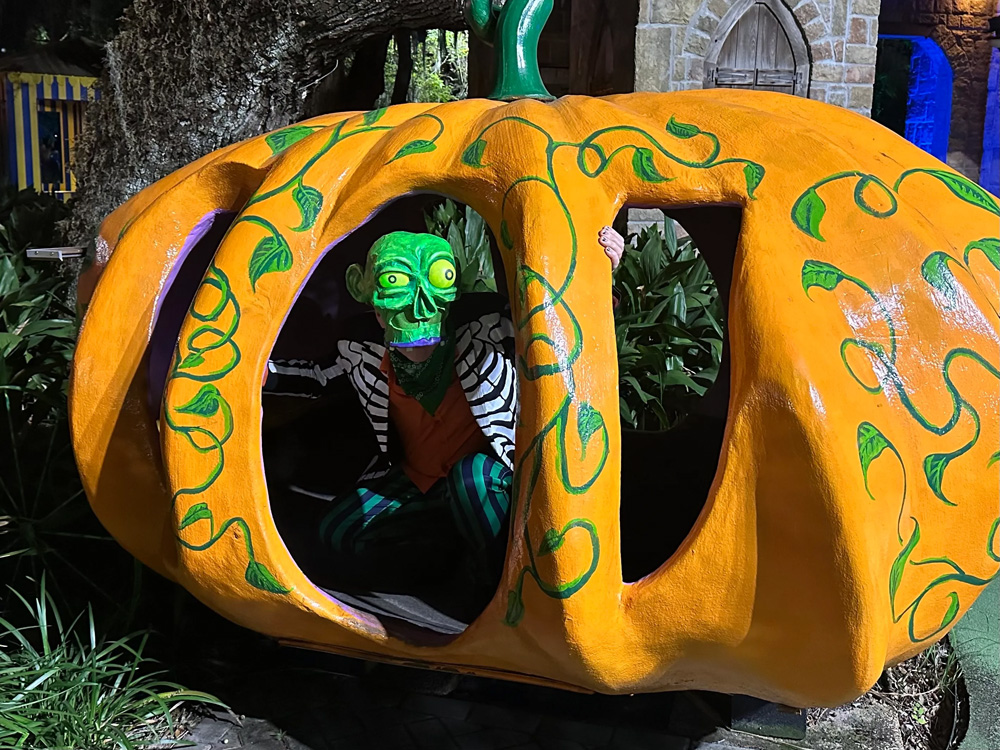 Me wearing the zombie mask and crouching spookily inside a big fiberglass pumpkin.