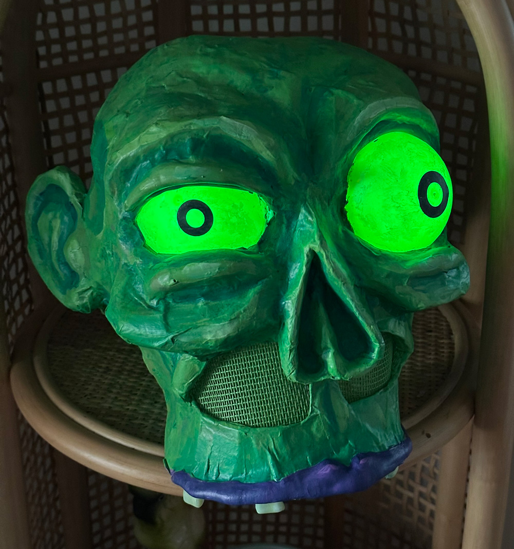 A close up of the green zombie mask with light-up eyes.