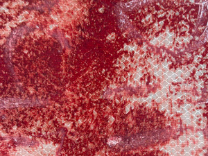Close up of a very scratched and faded stop sign; the damaged red surface shows a tiny grid pattern from the reflective material