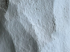 Close up of the bumpy fake stone pattern on a piece of siding on a house