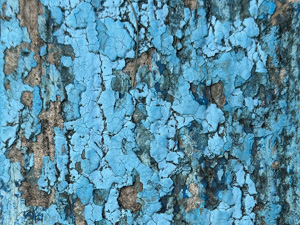 Very chipped and peeling light blue paint on the curb.