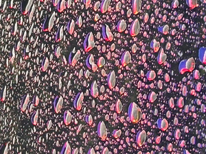 Rain drops on a windshield; they look like they're sort of glowing pink due to some strange property of the glass, like maybe it had a weird tinted coating or something.