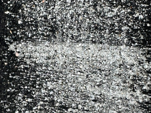 Zoomed in view of an area where someone had painted the sidewalk black and now most of the paint has been worn off, creating a very high contrast grainy texture.